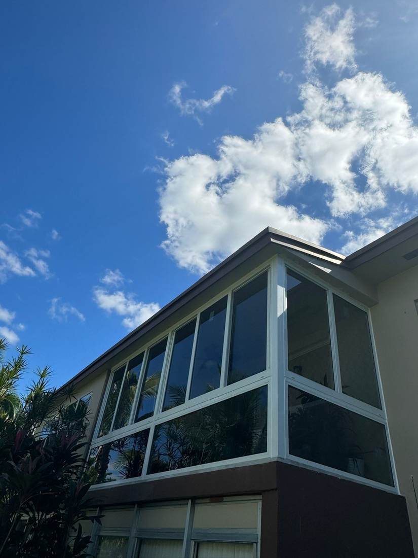 Low-angle view of a condo balcony enclosure with new white-frame impact windows