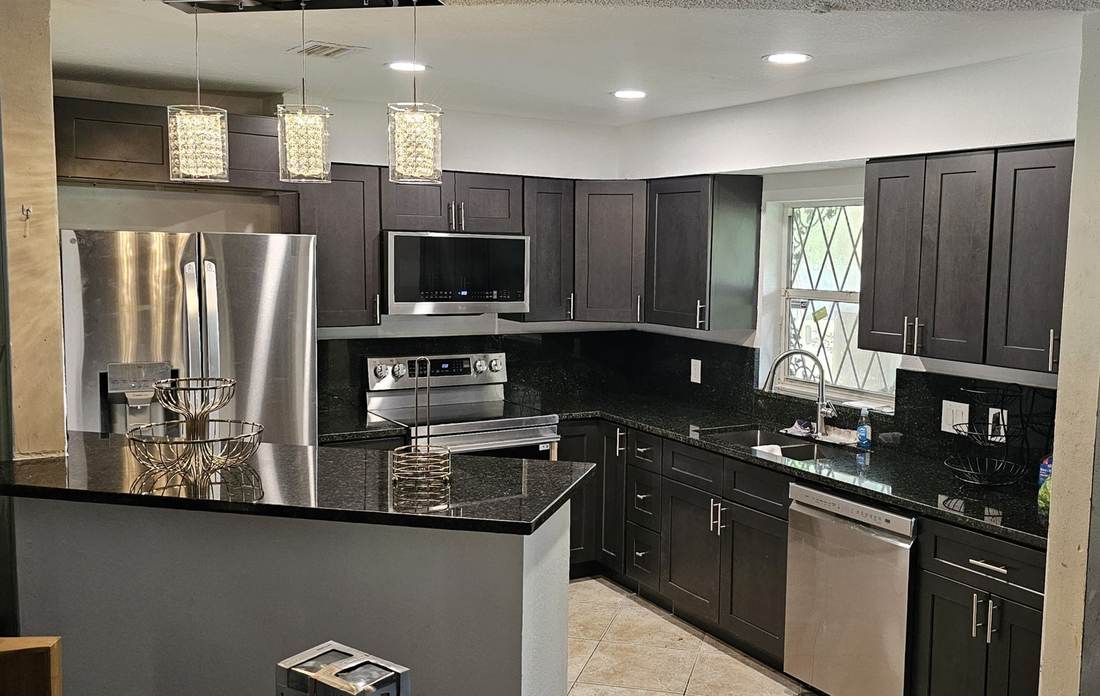 Remodeled kitchen with espresso shaker cabinets, black granite countertops, crystal pendants and stainless appliances