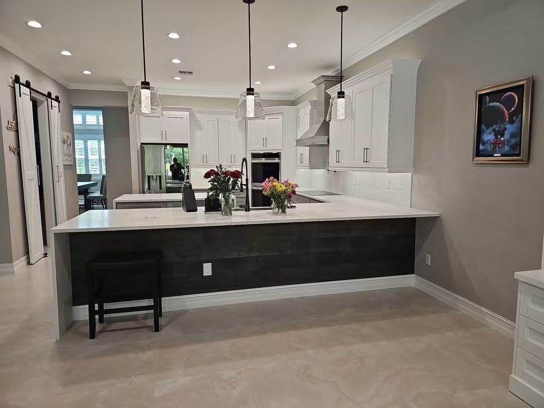 Open kitchen remodel with white shaker cabinets, quartz waterfall peninsula and glass pendant lights
