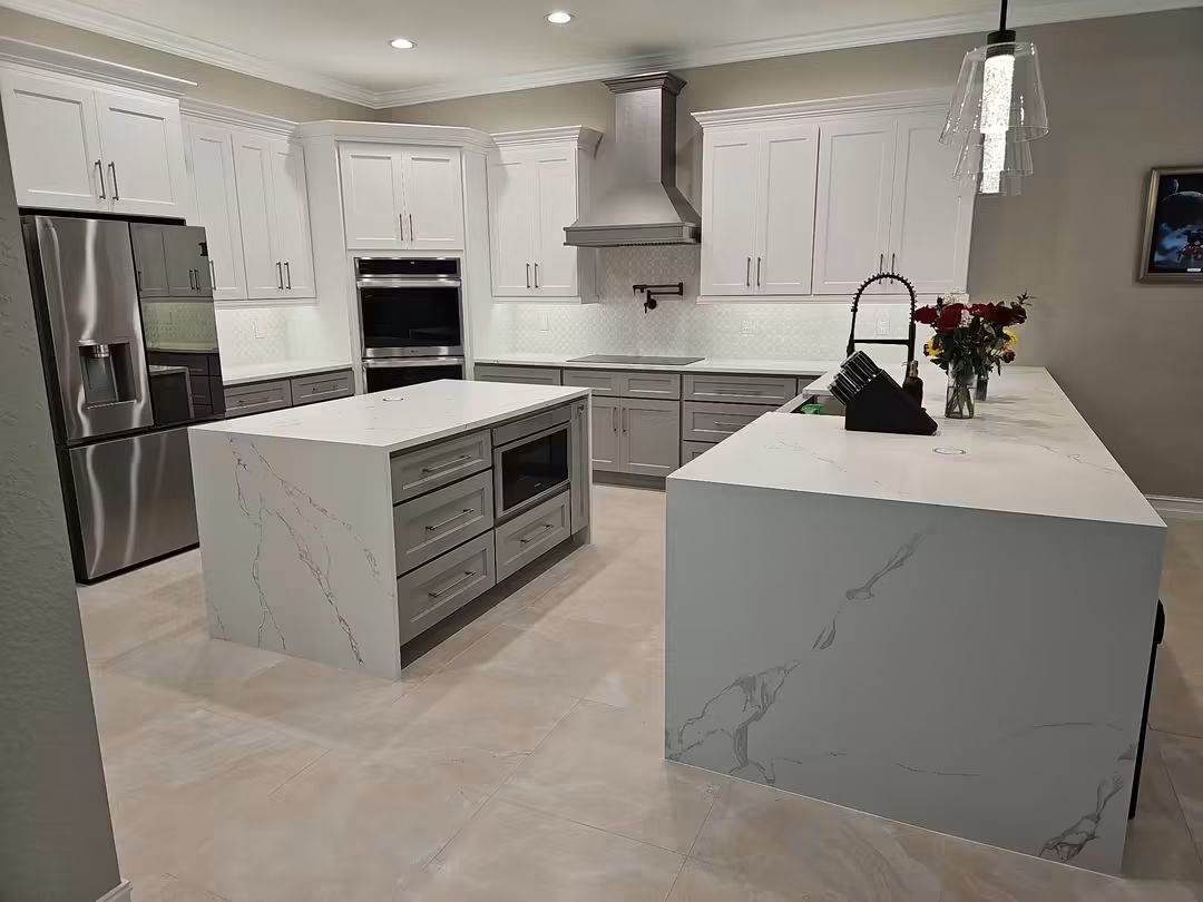 Kitchen with quartz waterfall island, gray lower cabinets and stainless range hood