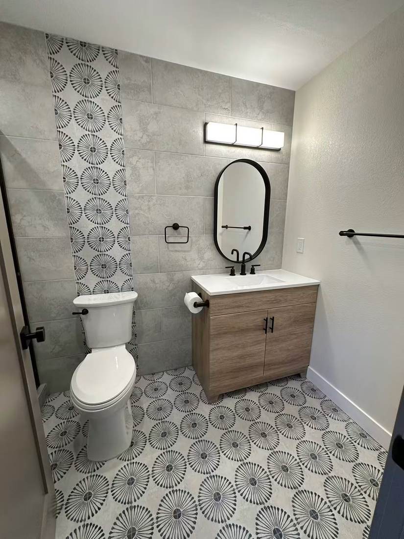 Powder room with patterned porcelain floor, accent tile stripe and wood vanity