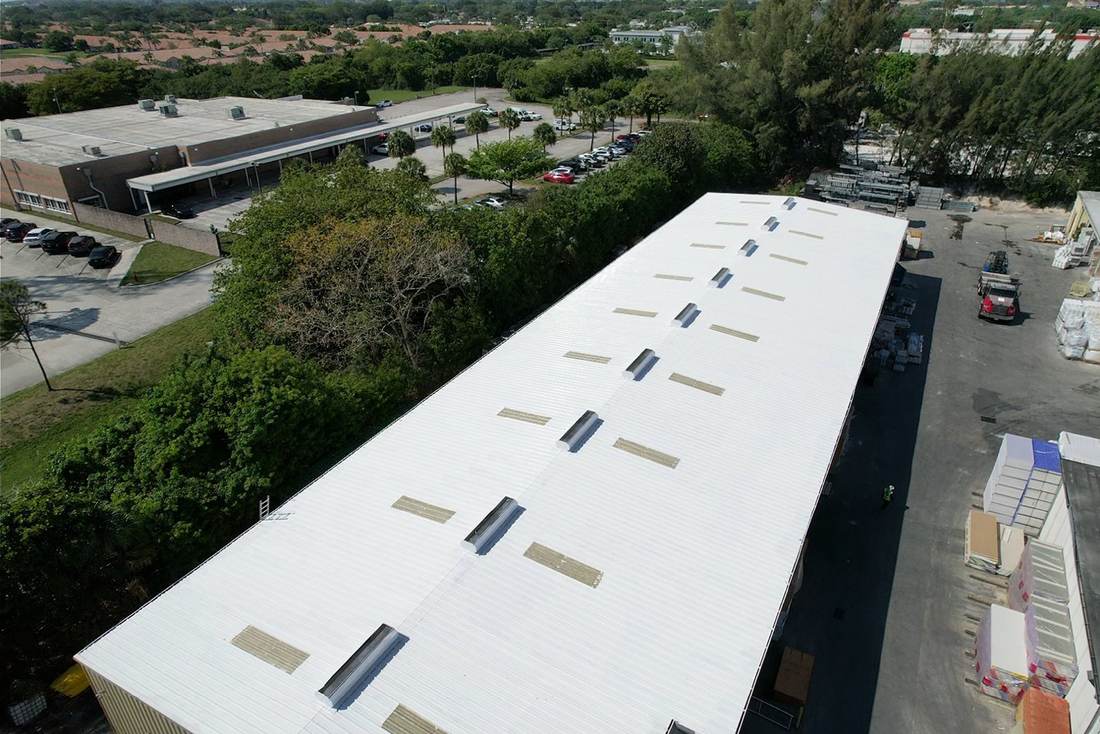 Long commercial warehouse with a restored bright white metal roof and skylights