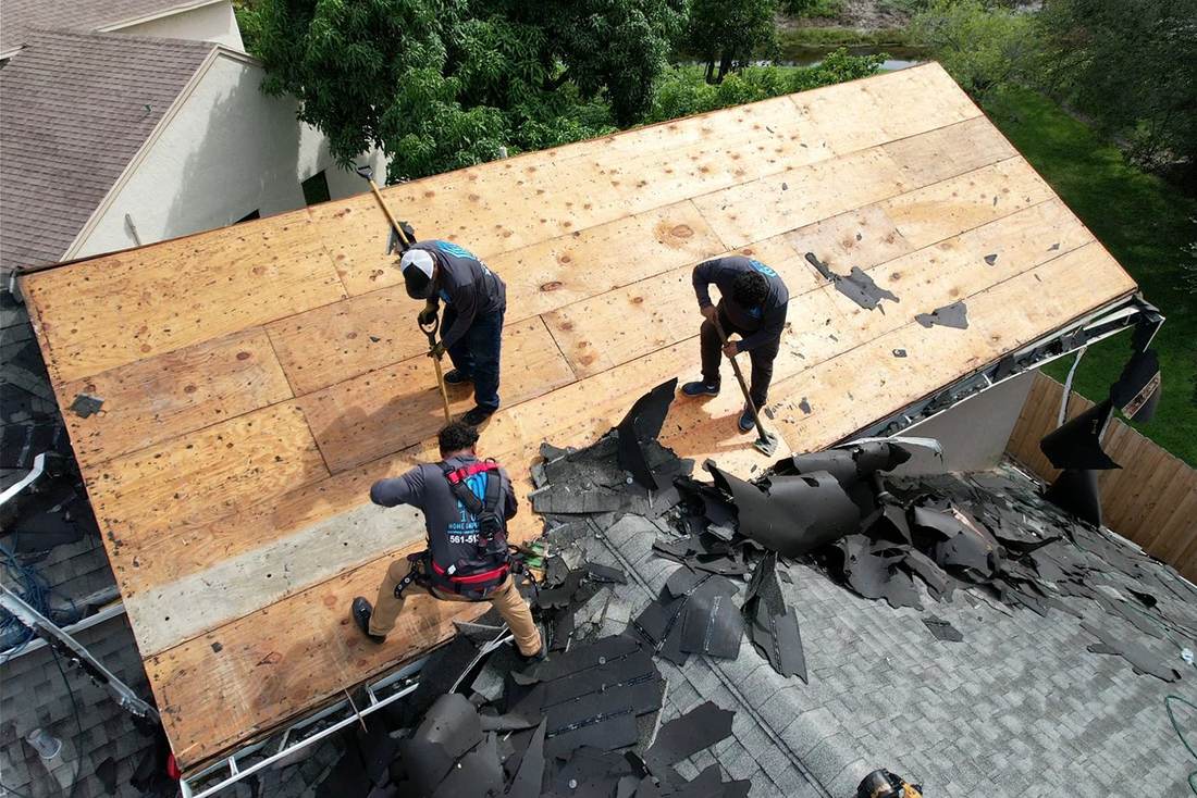 Roofers in 1 OAK shirts working on new plywood roof decking during a shingle replacement