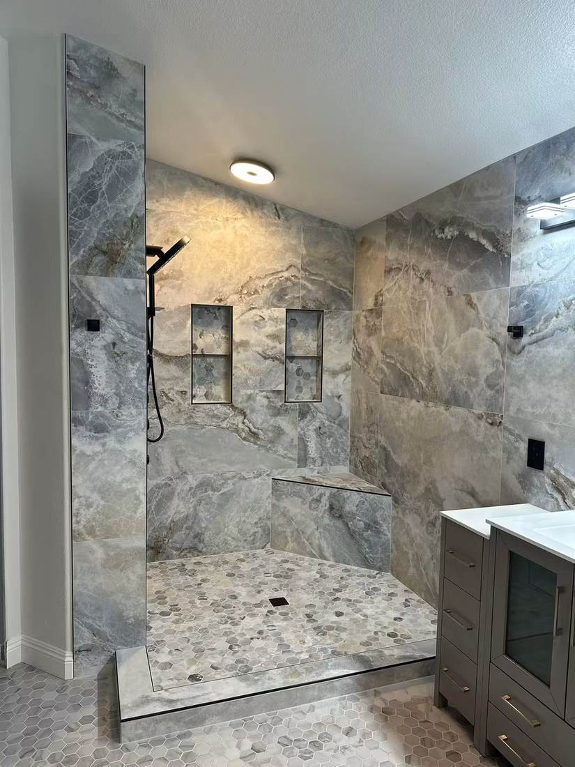 Walk-in shower with large-format marble-look tile, built-in bench and recessed niches